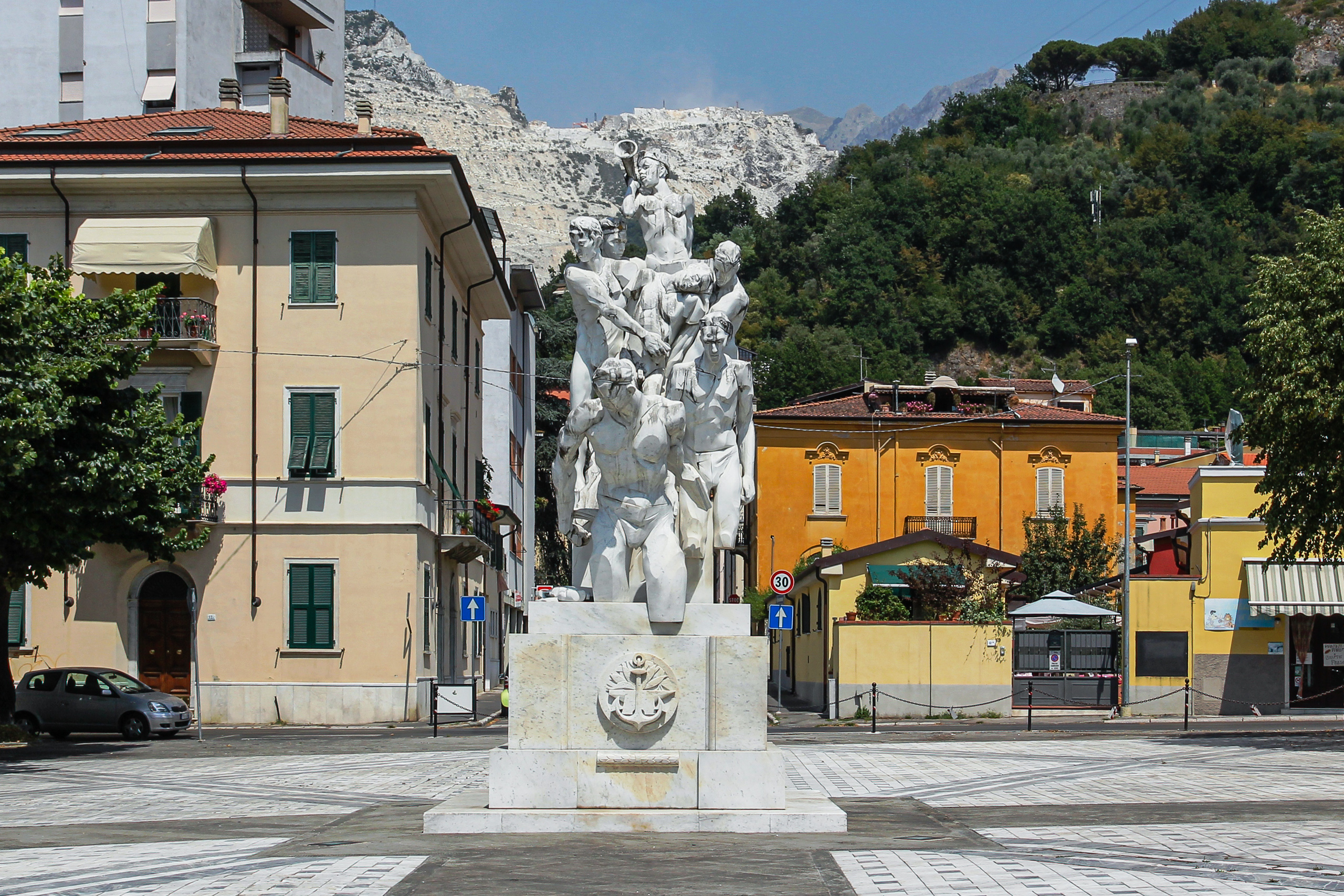Marmordenkmal mitten auf dem Platz, dahinter der aufgeschnittene Berg